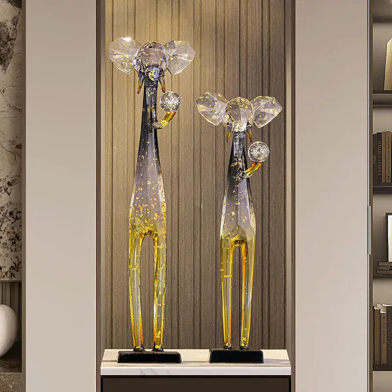 Two tall glass giraffe sculptures with translucent blue and amber bodies and golden speckles for floor decoration sculpture