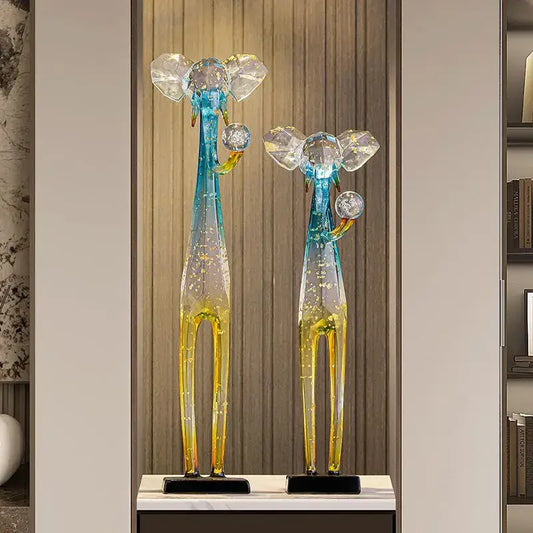 Two translucent glass giraffe floor decoration sculptures with blue and yellow gradient bodies on black bases