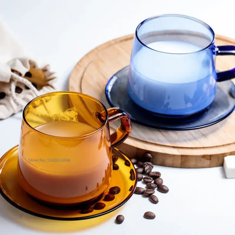 Amber-colored heat resistant glass coffee mug with matching saucer filled with milk and scattered coffee beans