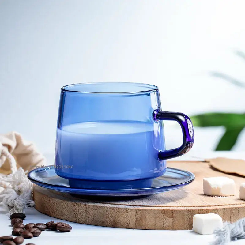 A translucent cobalt blue glass coffee mug with a matching saucer and heat resistant modern minimalist design