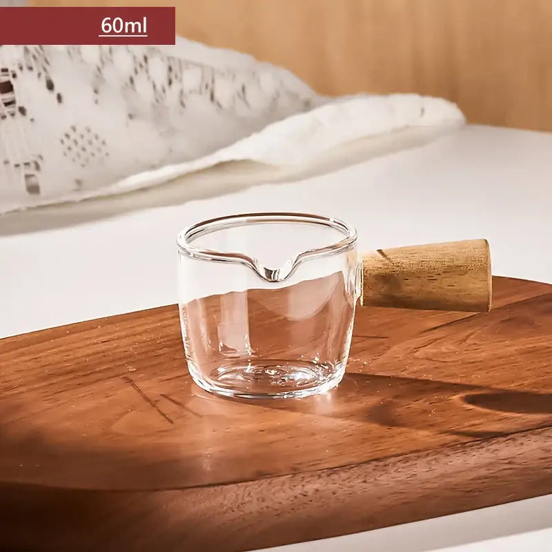 Transparent glass espresso measuring cup with wood handle and spout marked 60ml for precise measuring