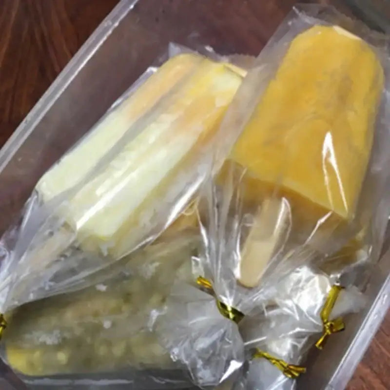 Yellow and white layered ice cream in transparent pink ice cream bags tied with gold ribbons for kitchen storage
