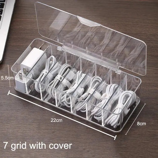 Transparent clear plastic cable storage box with seven compartments and lid for organizing white cables and adapters