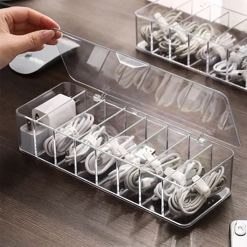 Transparent plastic cable storage box with multiple compartments holding white charging cords for decorbites cable storage