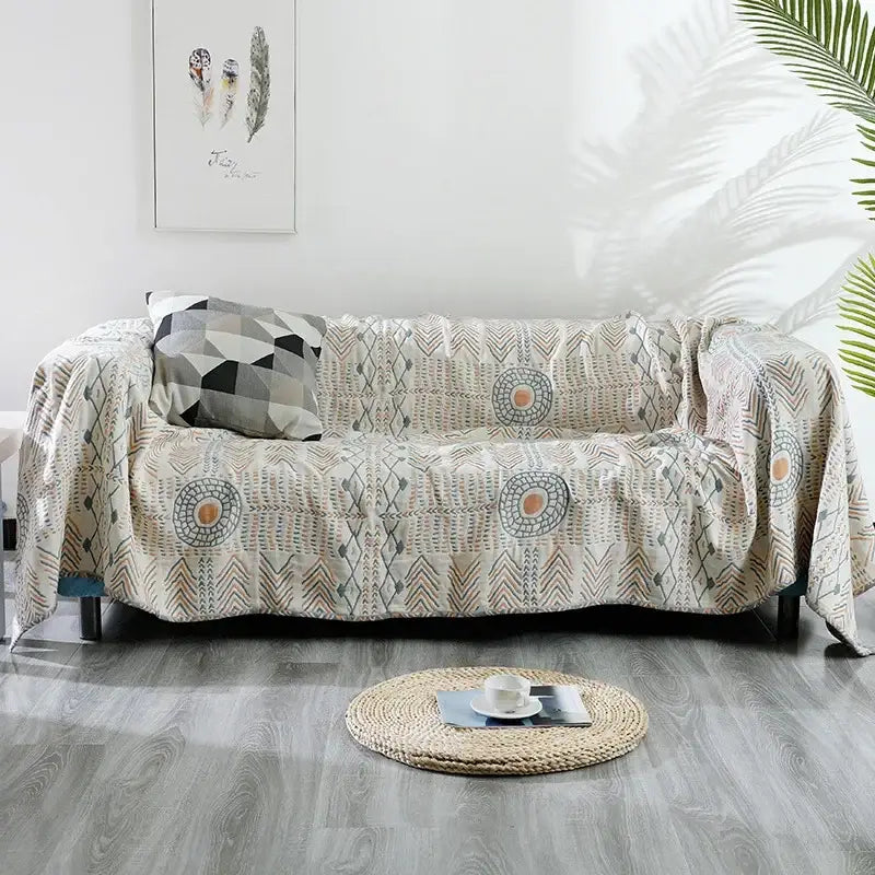 Beige quilted cotton sofa throw blanket with geometric and circular patterns in gray beige and muted orange tones