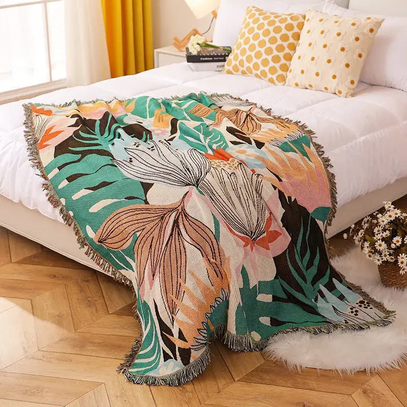 A vibrant cozy knit throw blanket with tropical leaf pattern in teal pink orange and black for decorbites cozy knit decor