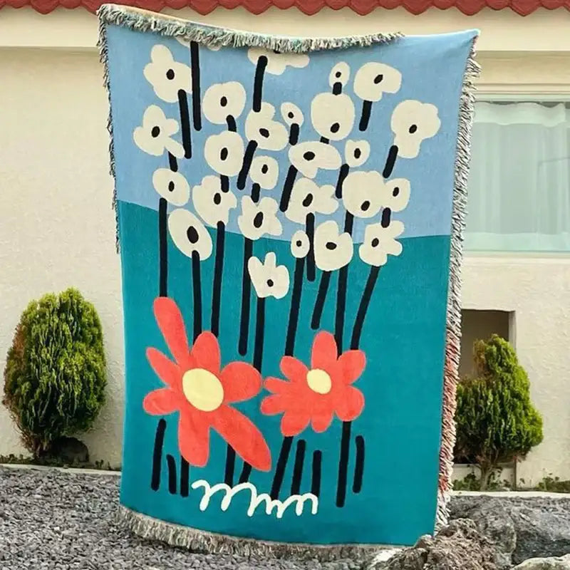 A vibrant blue cozy knit throw blanket with stylized floral design and fringed edges for decorbites cozy knit decor