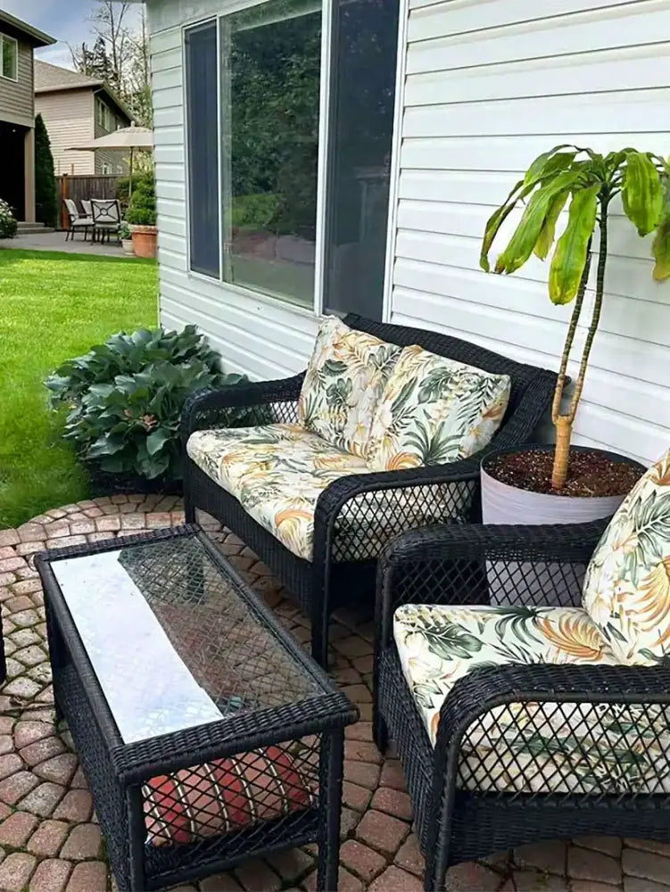 Black wicker patio sofa set with tropical leaf patterned cushions in green and cream brushed polyester microfiber