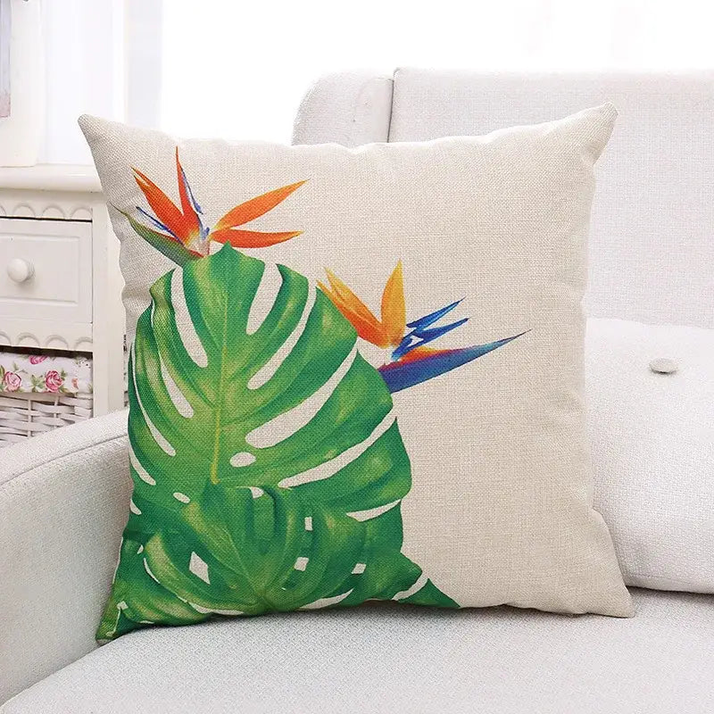 Beige linen cushion cover featuring vibrant tropical green plant leaves and orange-blue bird of paradise decorbites design