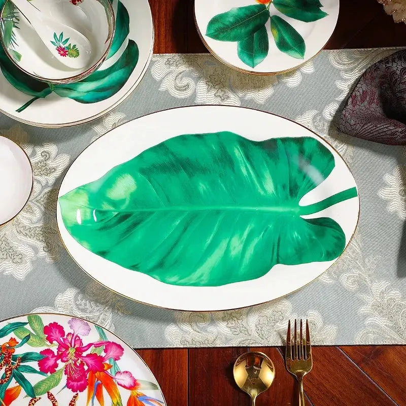 Oval white ceramic platter with gold rim featuring vibrant green leaf collection monstera design for dining room use