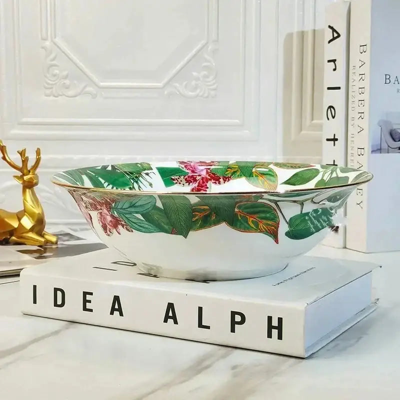 A white porcelain bowl from the tropical green leaf collection with green leaves pink flowers and gold trim