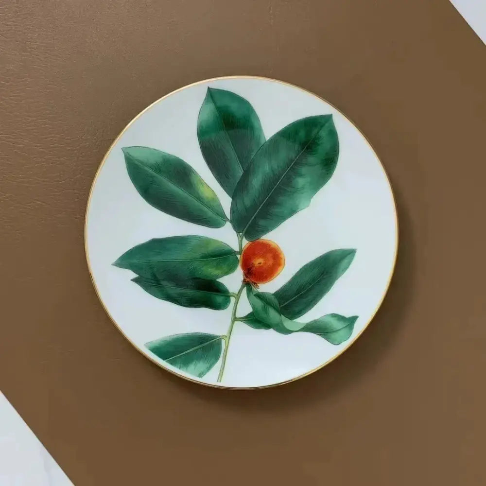 A porcelain white ceramic plate with gold rim and tropical green leaf collection design for an elegant dining experience