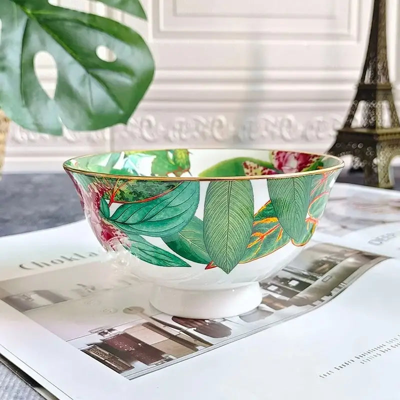 A white porcelain bowl with gold trim featuring green leaf collection botanical pattern for tea set dining room
