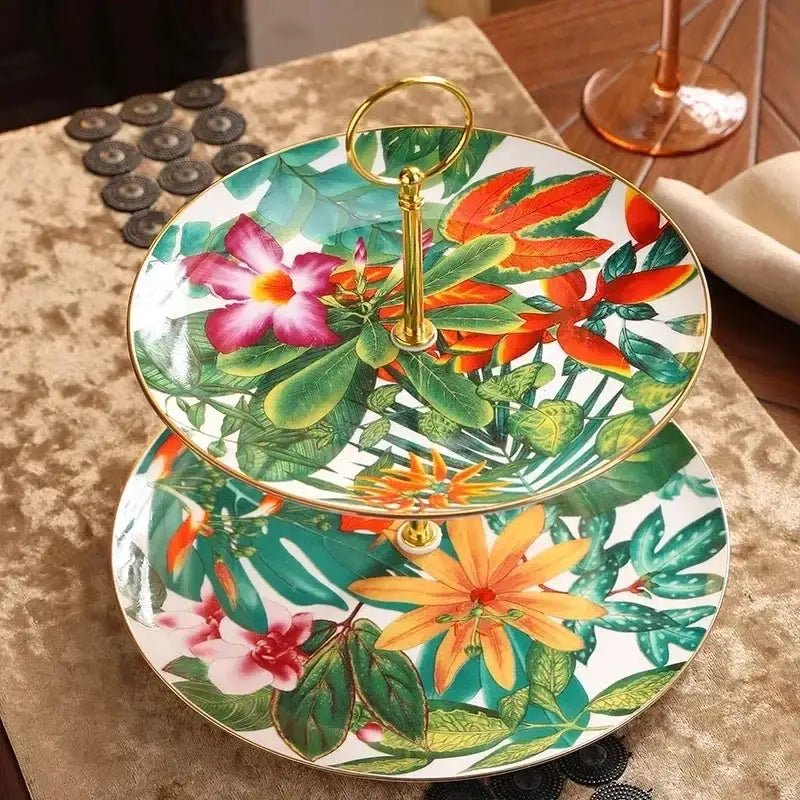 Two-tiered porcelain dessert stand with tropical green leaf collection floral design for elegant dining experience
