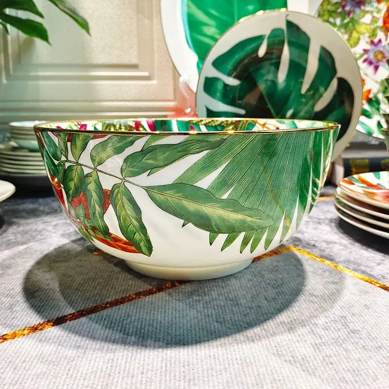 A white porcelain bowl with a gold rim and vibrant green leaf patterns enhancing the green leaf collection dining experience
