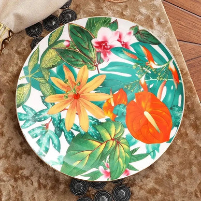 A vibrant tropical floral porcelain tea plate with bold orange pink yellow blossoms and green leaf collection design for dining experience