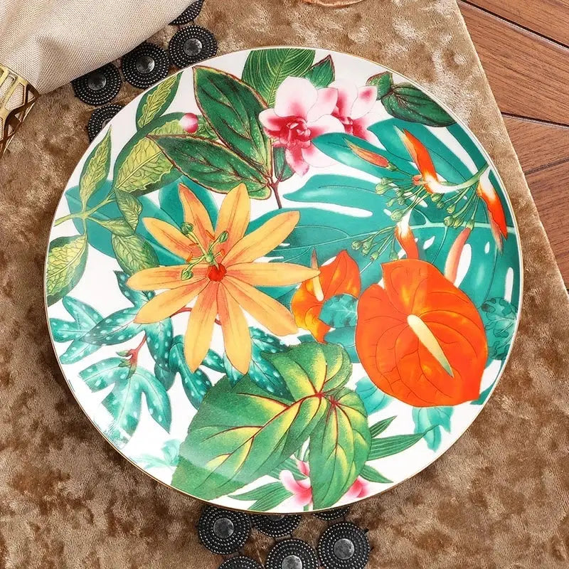 A vibrant tropical floral porcelain tea plate with bold orange pink yellow blossoms and green leaf collection design for dining experience