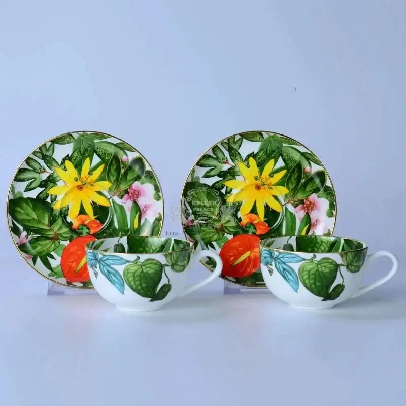 A pair of white porcelain teacups with vibrant yellow flowers pink blossoms and green leaf collection designs