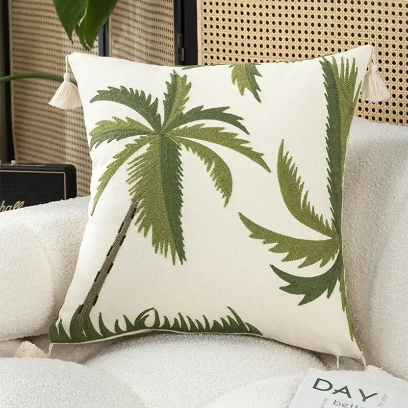White cushion cover with embroidered green palm trees and cream tassels in tropical olive and cream patchwork design