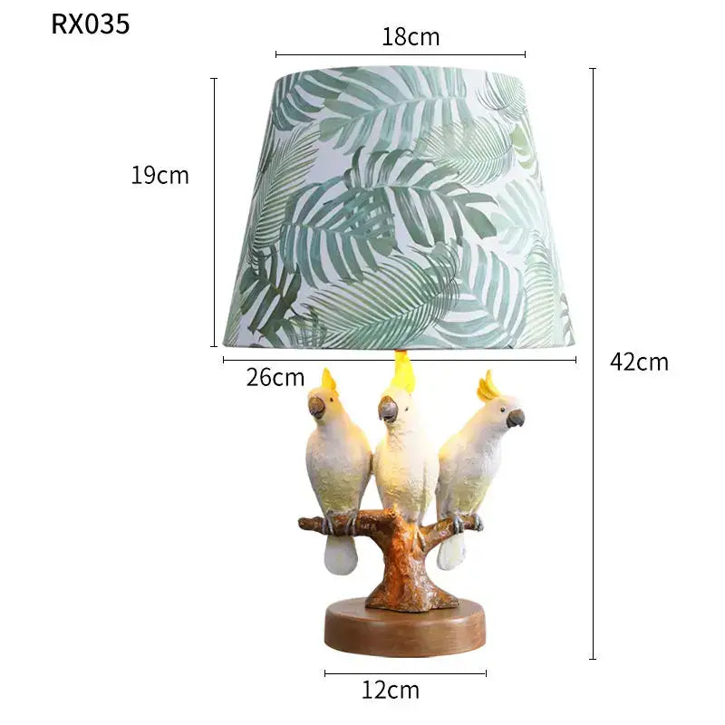 Tropical parrot desk lamp with three white cockatoo figurines on tree branch base and green leaf conical shade decorbites cartoon parrot