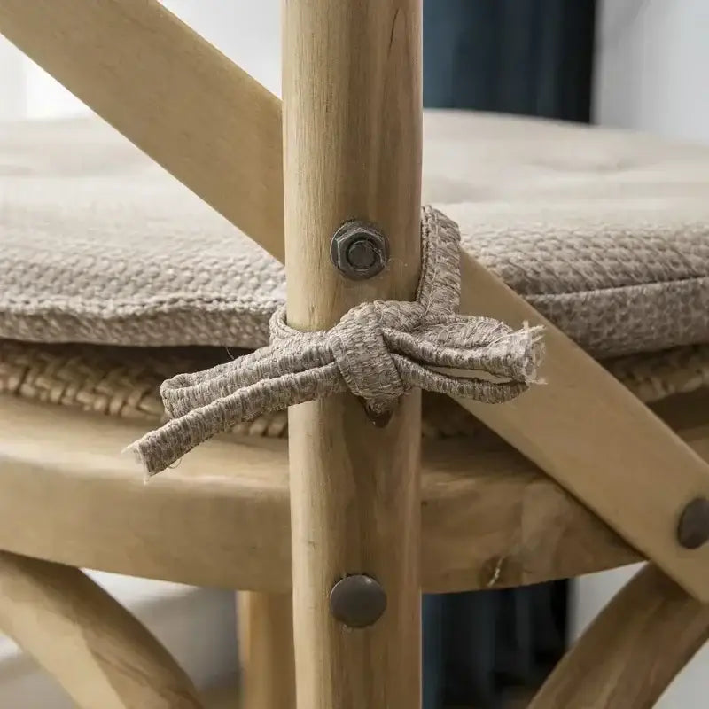 Beige woven fabric tie securing tufted beige textured dining chair cushions on wooden frame of decorbites dining chair