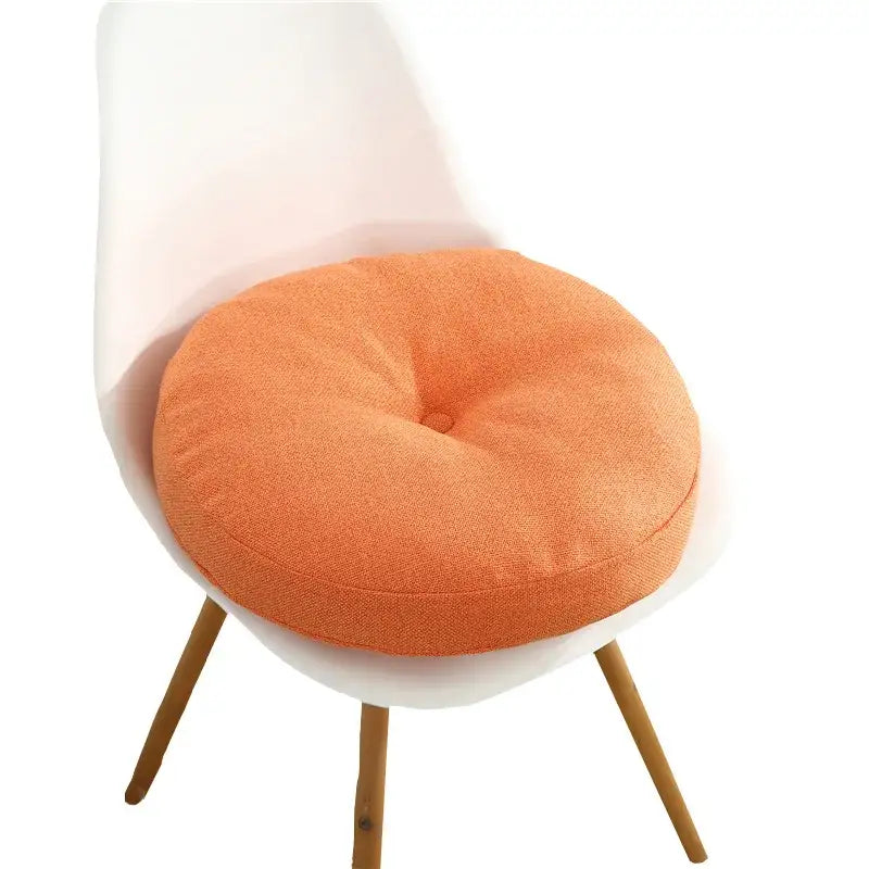 Orange circular floor pillow seating cushion with textured fabric and central button detail for living room use