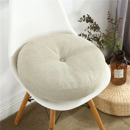 Beige linen round seating cushion with central button tuft for floor pillow seating and living room pouf use