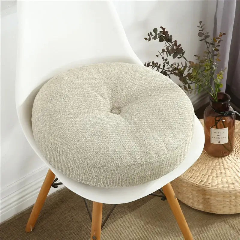 Beige linen round seating cushion with central button tuft for floor pillow seating and living room pouf use