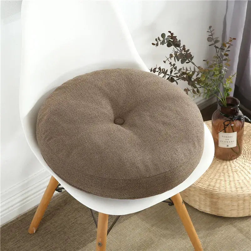 Brown textured fabric round seating cushion with central button detail for living room floor pillow seating pouf