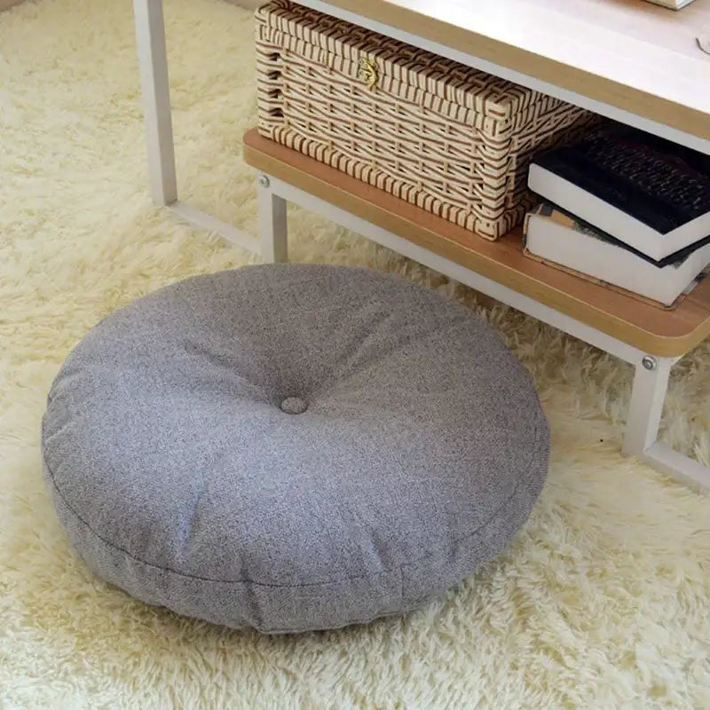 Tufted grey linen floor pillow seating cushion with a circular shape and textured fabric for living room use