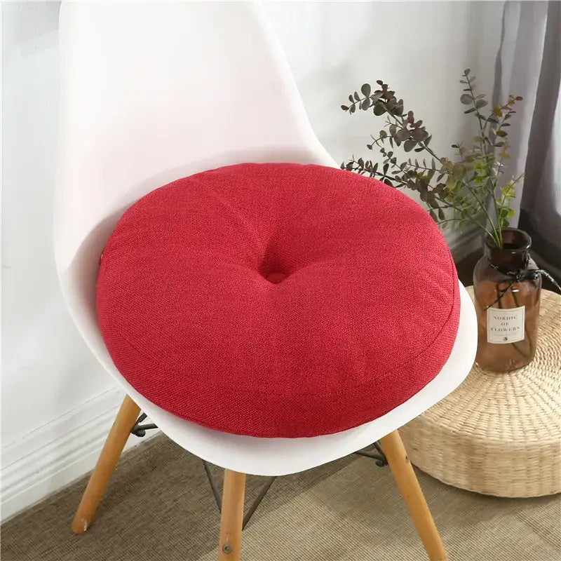 Red circular seating cushion with textured fabric and central indentation suitable for floor pillow seating pouf use