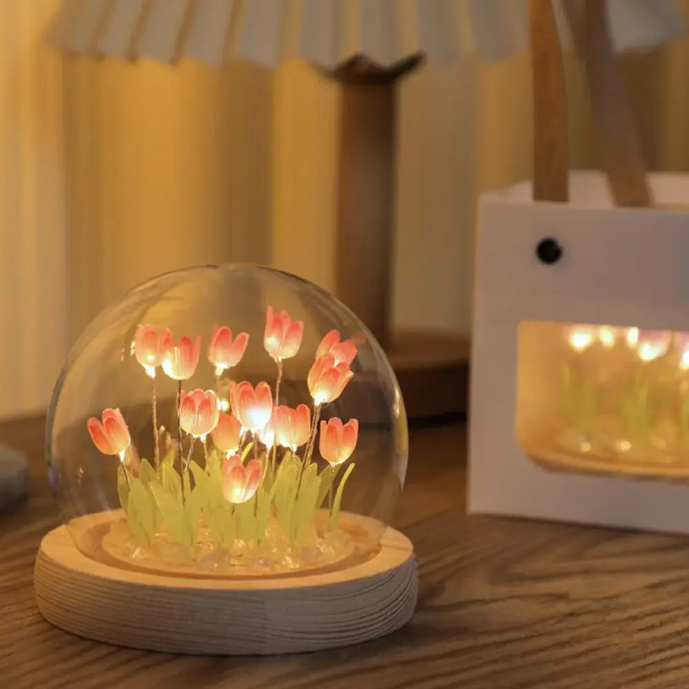 A clear glass dome with illuminated pink tulips and green stems on a wooden base tulip night light bedside lamp