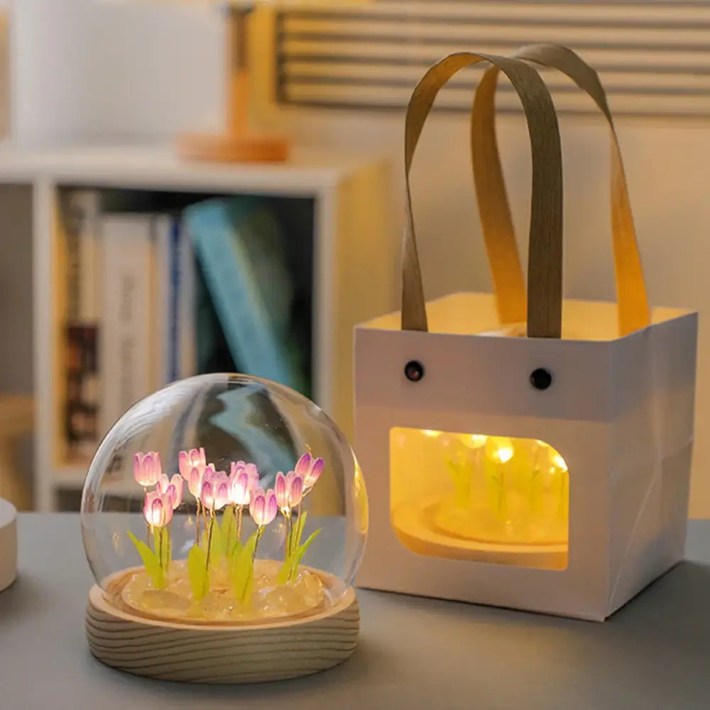 A clear glass dome containing glowing pink tulips on a wooden base tulip night light battery operated bedside lamp
