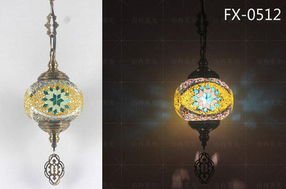 Mosaic globe pendant light with intricate starburst pattern and dangling metal ornament, featuring a mix of green, yellow, blue, and gold colors.