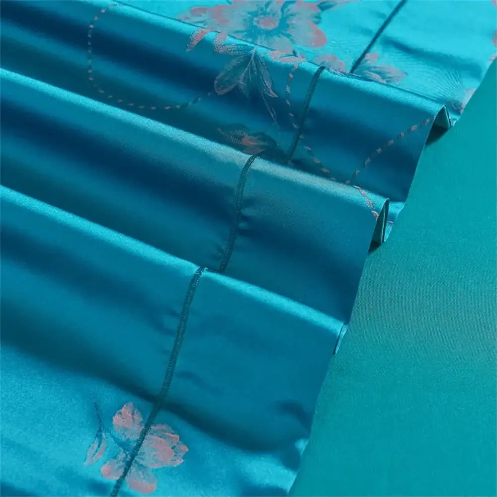 Turquoise blue satin jacquard bedding set featuring a teal satin pillowcase with delicate pink and blue floral embroidery
