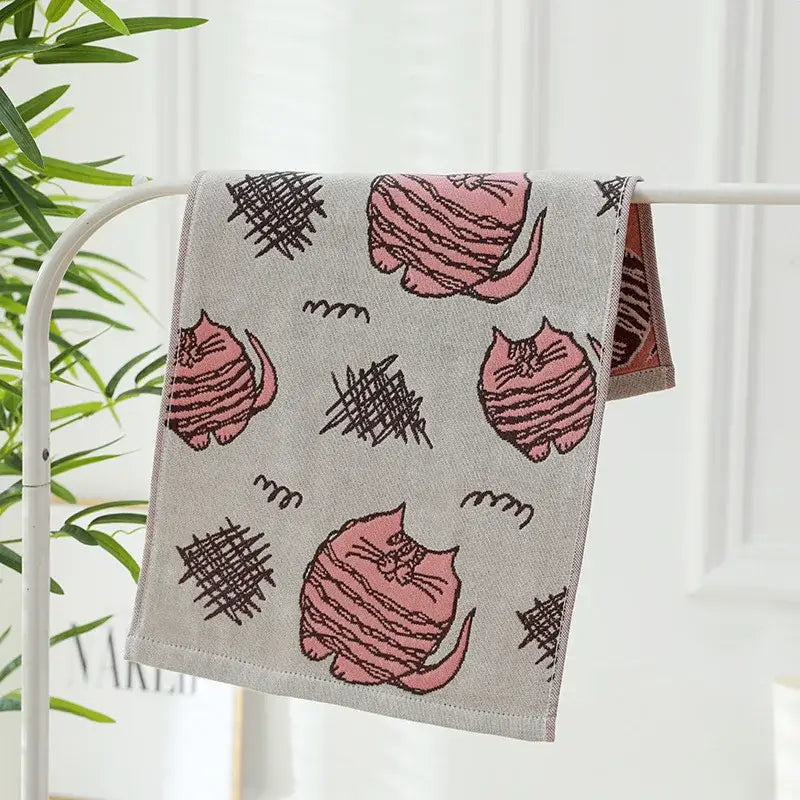 A soft gray cotton gauze face towel with pink striped cartoon cats and black scribble shapes decorbites cotton gauze