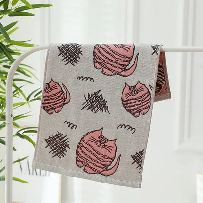 A soft gray cotton gauze face towel with pink striped cartoon cats and black scribble shapes decorbites cotton gauze