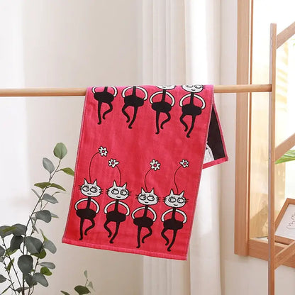 A vibrant pink decorbites cotton gauze face towel with playful black and white cartoon cats in ballet poses and flowers