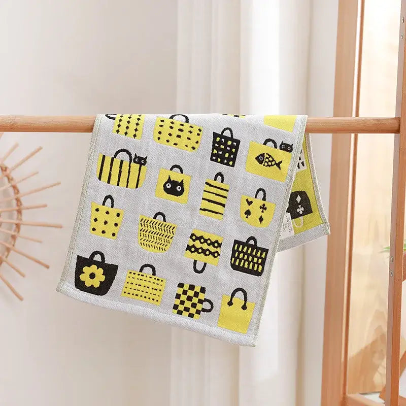 A gray decorbites cotton gauze face towel with yellow and black shopping bags and playful cat and flower patterns