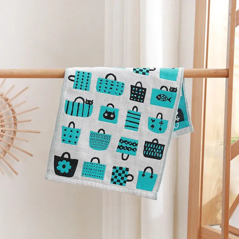 A light gray decorbites cotton gauze face towel with turquoise cartoon cats and shopping bag patterns for bathroom use