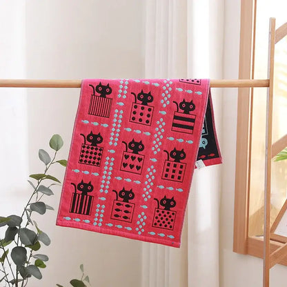 A vibrant pink decorbites cotton gauze face towel with playful black cats and blue fish ideal for hand and face use