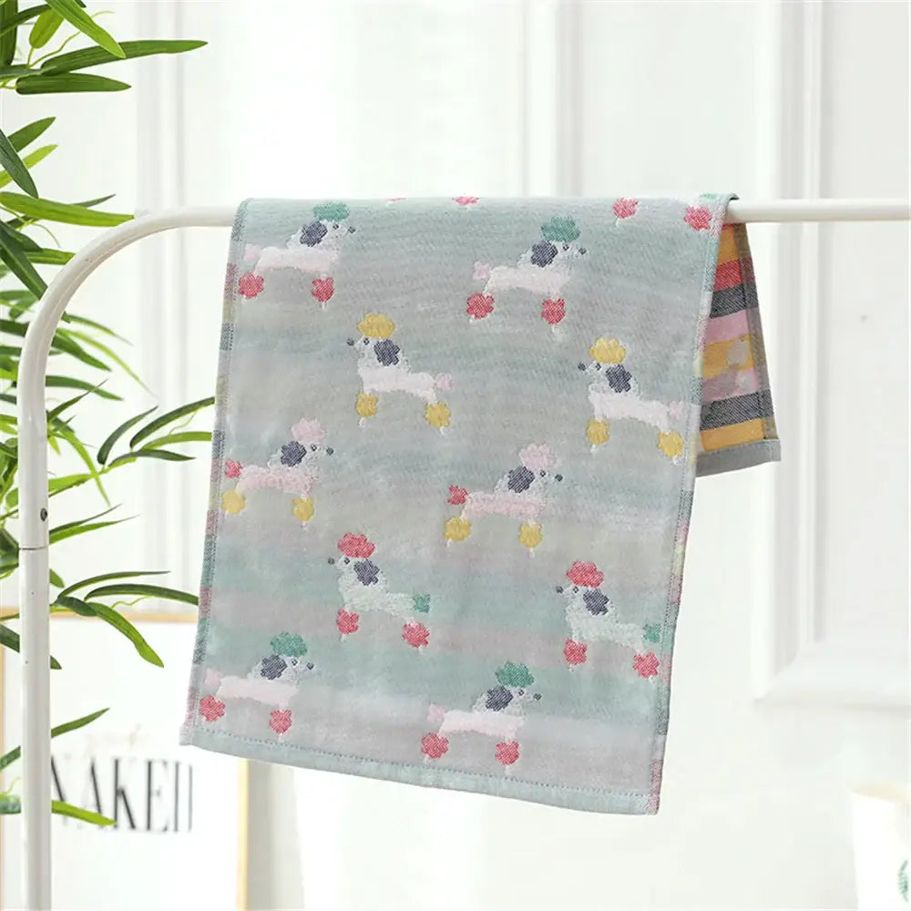 A light blue cotton gauze hand towel with playful cartoon poodles featuring colorful pom-poms from decorbites face towel set