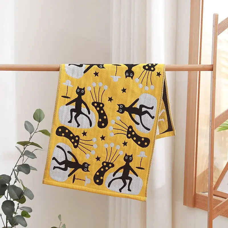 A vibrant yellow cotton gauze hand towel with playful black cat illustrations from decorbites face towel set