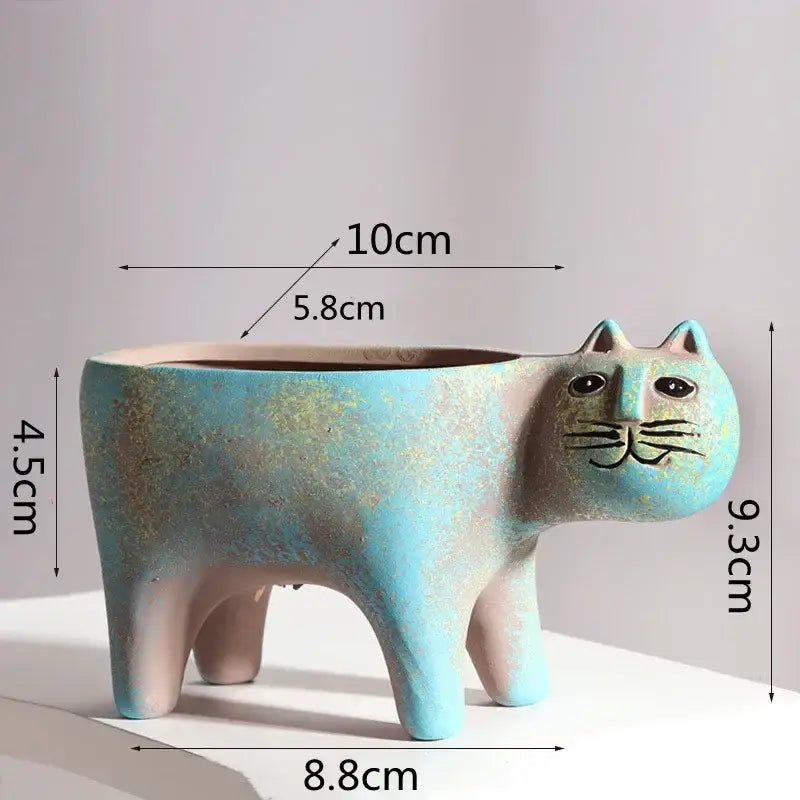 Turquoise ceramic cat-shaped succulent plant pot with black eyes, whiskers, and gold speckles for living room decor