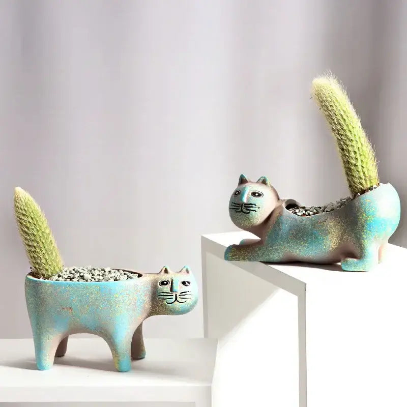 Two turquoise ceramic cat-shaped succulent plant pots with green cacti for living room decor