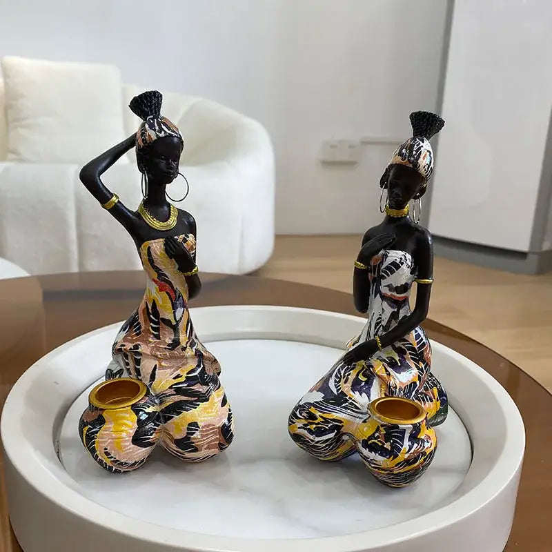 Two vibrant decorbites black woman candlestick ceramic figurines in patterned dresses with gold accents and matching pots