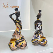 Two vibrant african black woman candlestick figurines with gold accents and patterned attire for living room decorbites black woman decor