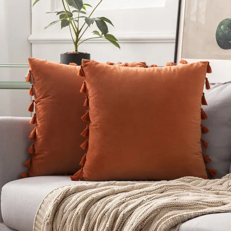 Two rust-colored velvet throw pillows with matching tassels for vibrant fringed tassel velvet living room decor