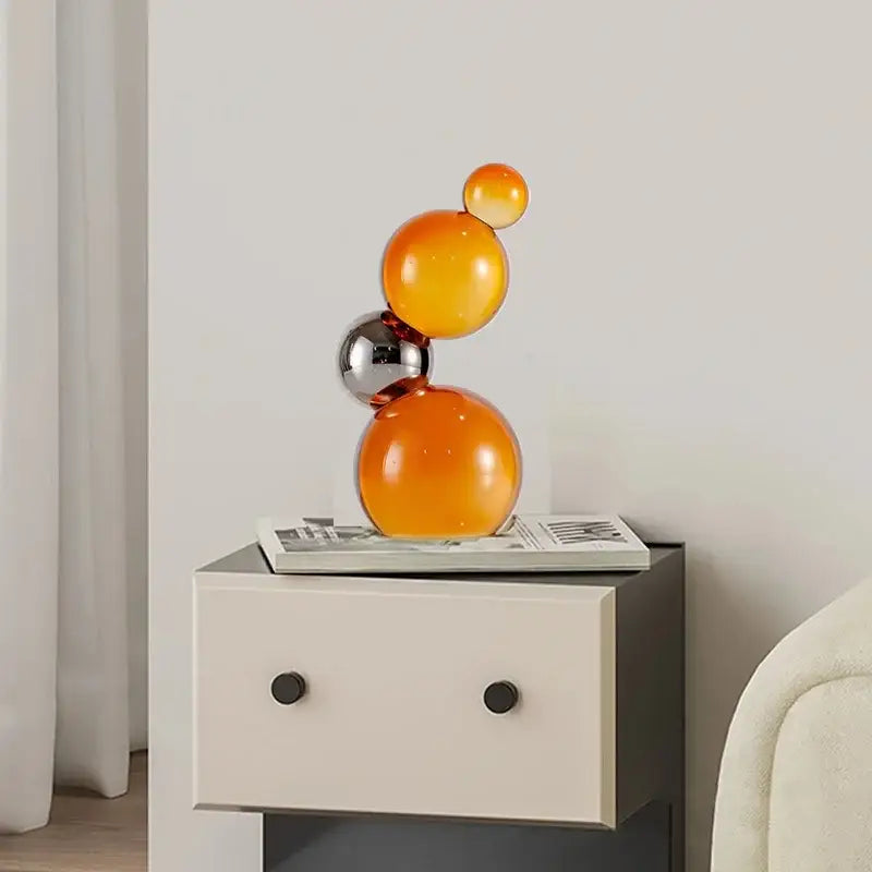 A modern glass sculpture of vibrant glossy crystal bubble decor spheres in gradient orange and reflective silver for home decor