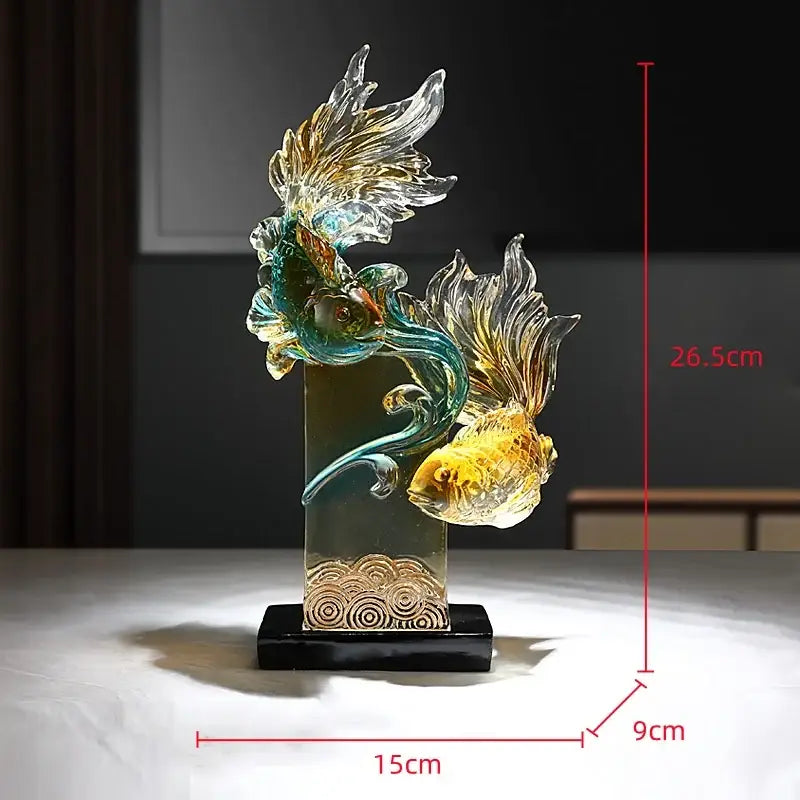 Translucent resin sculpture of teal and golden yellow decorbites gradient goldfish with flowing fins on black base for decor